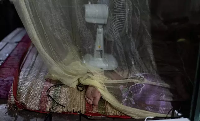 Do Hoang Trung, who lives on a houseboat with his twin sister and their grandmother, sleeps under a mosquito net in Can Tho, Vietnam, Jan. 17, 2024. (AP Photo/Jae C. Hong)