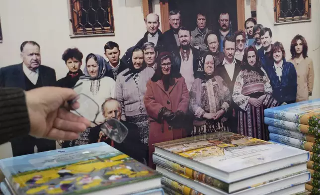Pavel Babka, gallerist and naïve art expert shows the photo of older generations of naïve painters in the village of Kovacica, Serbia, Thursday, Nov. 28, 2024. (AP Photo/Darko Vojinovic)