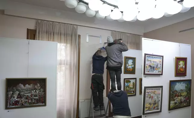 Workers put up air conditioner in the Gallery of naive art in the village of Kovacica, Serbia, Thursday, Nov. 28, 2024. (AP Photo/Darko Vojinovic)
