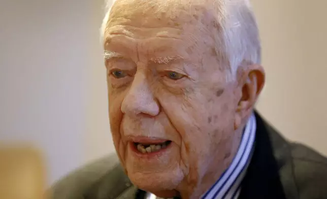 FILE - Former US President Jimmy Carter listens during a video interview with the Associated Press via a laptop at a hotel in London, Tuesday, Feb. 2, 2016. (AP Photo/Kirsty Wigglesworth, File)