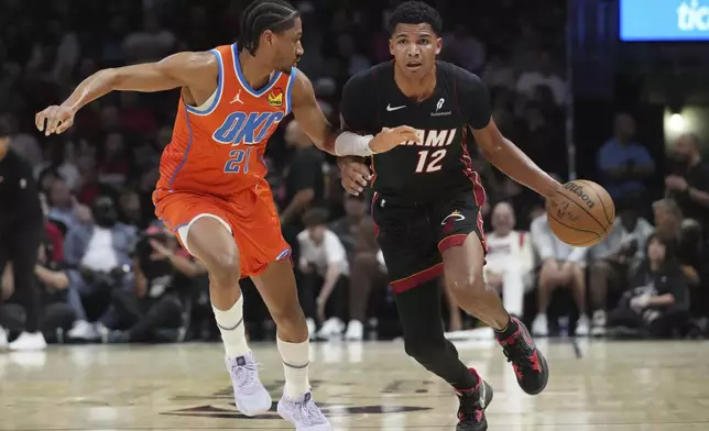 Miami Heat guard Dru Smith (12) dribbles the ball as Oklahoma City Thunder guard Aaron Wiggins (21) defends during the first half of an NBA basketball game, Friday, Dec. 20, 2024, in Miami. (AP Photo/Marta Lavandier)