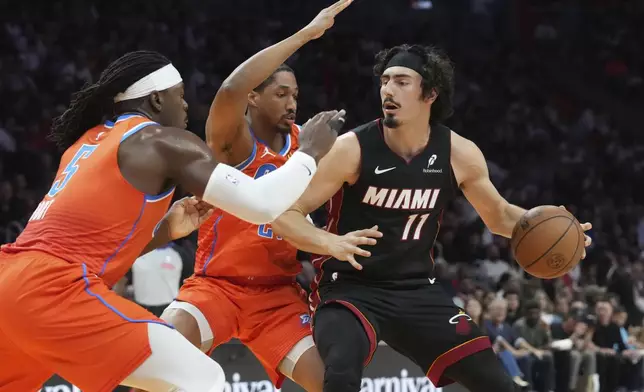 Oklahoma City Thunder guards Aaron Wiggins (21) andLuguentz Dort (5) defend Miami Heat guard Jaime Jaquez Jr. (11) during the first half of an NBA basketball game, Friday, Dec. 20, 2024, in Miami. (AP Photo/Marta Lavandier)