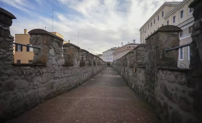 People walk along the elevated secret narrow 800-meter corridor, known as "Passetto", that runs atop the old Vatican walls between the Popes' Vatican palace and the Castel Sant'Angelo fortress, which was used during the Sack of Rome in 1527 by Pope Clement VII to escape and take refuge in the fortress, as it is reopened to the public just ahead of the Jubilee Year, an event expected to draw millions of visitors to the Eternal City, in Rome, Monday, Dec. 23, 2024. (AP Photo/Andrew Medichini)