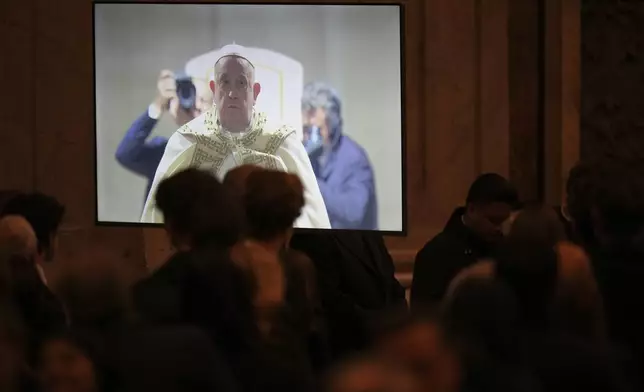 A giant monitor shows Pope Francis pausing before entering the holy door at the start of the Christmas Eve Mass in St. Peter's Basilica at The Vatican, Tuesday, Dec. 24, 2024, (AP Photo/Andrew Medichini)