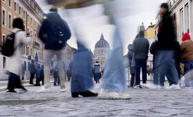 People stroll in the square leading from St. Angelo Castle to the St. Peter's Basilica above a newly inaugurated tunnel, a day before the start of the 2025 Jubilar year, which allows the square to be a fully pedestrian area, in Rome, Monday, Dec. 23, 2024. (AP Photo/Gregorio Borgia)