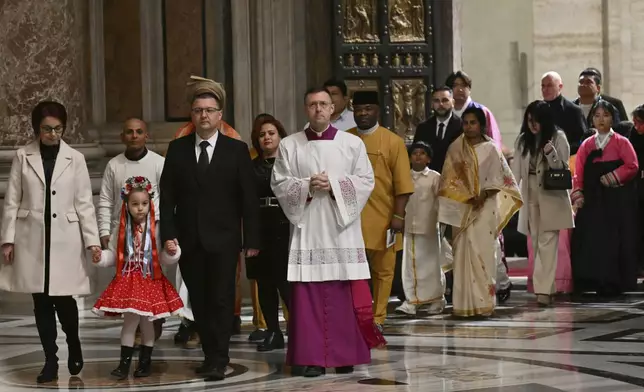 The first pilgrims pass through after Pope Francis opened the Holy Door to mark the opening of the 2025 Catholic Holy Year, or Jubilee, in St. Peter's Basilica, at the Vatican, Tuesday Dec. 24, 2024. (Alberto Pizzoli/Pool via AP)