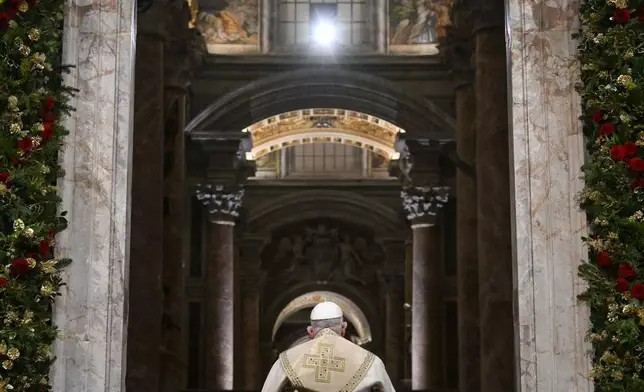 In this image released by Vatican Media, Pope Francis opens the holy door marking the start of the Catholic jubilar year 2025 before presiding over the Christmas Eve Mass in St. Peter's Basilica at The Vatican, Tuesday, Dec. 24, 2024. (AP Photo/Vatican Media, HO)