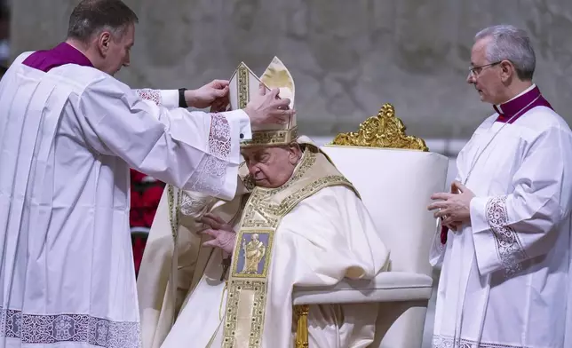 Pope Francis is helped by masters of ceremonies Massimiliano Matteo Boiardi, left, and Diego Giovanni Ravelli, right, as he presides over the Christmas Eve Mass in St. Peter's Basilica at The Vatican, Tuesday, Dec. 24, 2024, after opening the basilica's holy door marking the start of the Catholic jubilar year 2025. (AP Photo/Andrew Medichini)