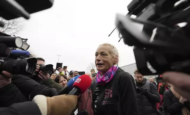 Belgian ultra runner Hilde Dosogne, center, is interviewed after crossing the finish line of her 366th consecutive marathon in Ghent, Belgium, Tuesday, Dec. 31, 2024. (AP Photo/Virginia Mayo)