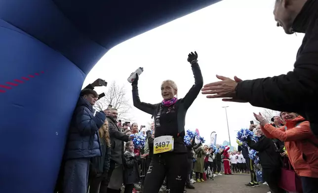 Belgian ultra runner Hilde Dosogne, center, is cheered on as she crosses the finish line during her 366th consecutive marathon in Ghent, Belgium, Tuesday, Dec. 31, 2024. (AP Photo/Virginia Mayo)