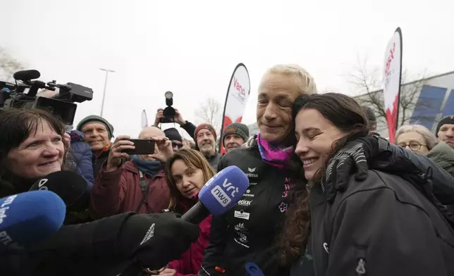 Belgian ultra runner Hilde Dosogne, center, hugs her daughter Lucie after crossing the finish line of her 366th consecutive marathon in Ghent, Belgium, Tuesday, Dec. 31, 2024. (AP Photo/Virginia Mayo)