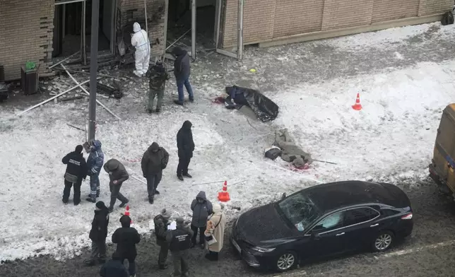 EDS NOTE: GRAPHIC CONTENT - Investigators work at the place where Lt. General Igor Kirillov, center, the head of Russia's Nuclear, Biological, and Chemical Defence Forces and his assistant, right, were killed by an explosive device planted close to a residential apartment's block in Moscow, Russia, Tuesday, Dec. 17, 2024. (AP Photo)