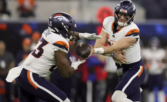 Denver Broncos quarterback Bo Nix, right, hands off to running back Audric Estime (23) during the first half an NFL football game against the Los Angeles Chargers, Thursday, Dec. 19, 2024, in Inglewood, Calif. (AP Photo/Ryan Sun)