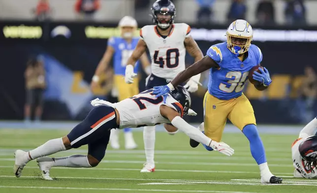 Los Angeles Chargers running back Kimani Vidal (30) is tackled by Denver Broncos safety Brandon Jones (22) during the first half an NFL football game Thursday, Dec. 19, 2024, in Inglewood, Calif. (AP Photo/Ryan Sun)