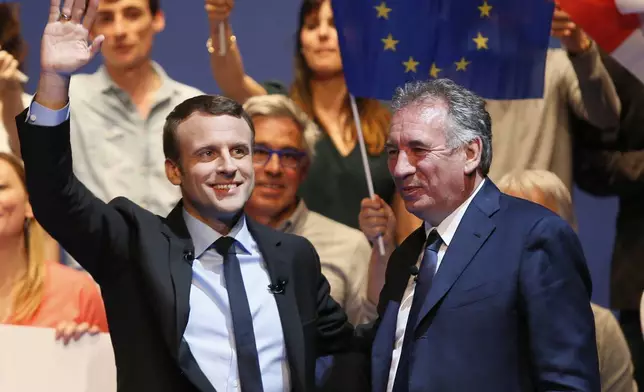 FILE - French centrist presidential election candidate Emmanuel Macron, left, waves supporters as French centrist politician Francois Bayrou looks on during a meeting in Pau, southwestern France, Wednesday, April 12, 2017. (AP Photo/Bob Edme, File)