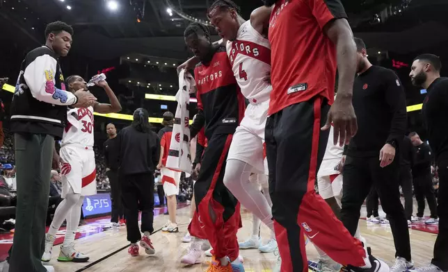 Toronto Raptors forward Scottie Barnes (4) is helped off the court after suffering an injury during the second half of an NBA basketball game against the New York Knicks, in Toronto, Monday, Dec. 9, 2024. (Nathan Denette/The Canadian Press via AP)