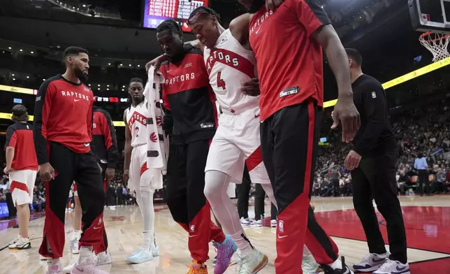 Toronto Raptors forward Scottie Barnes (4) is helped off the court after suffering an injury during the second half of an NBA basketball game against the New York Knicks, in Toronto, Monday, Dec. 9, 2024. (Nathan Denette/The Canadian Press via AP)