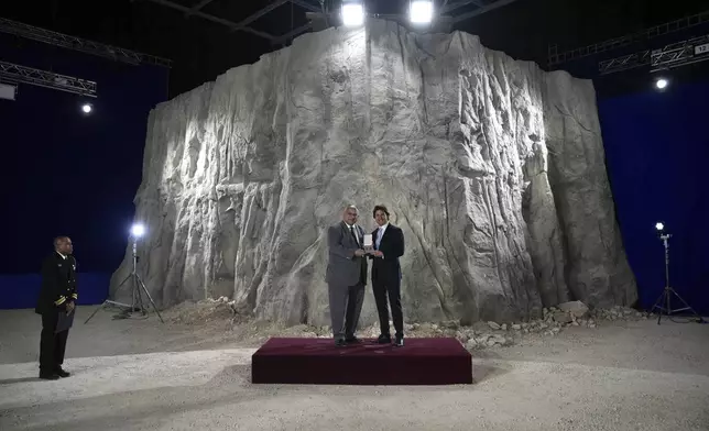 Tom Cruise, right, receives a Navy Distinguished Public Service Award from The United States Secretary of the Navy Carlos Del Toro presents at the Longcross South Studios, in Runnymede, Surrey, England, Tuesday, Dec. 17, 2024. (AP Photo/Kin Cheung)