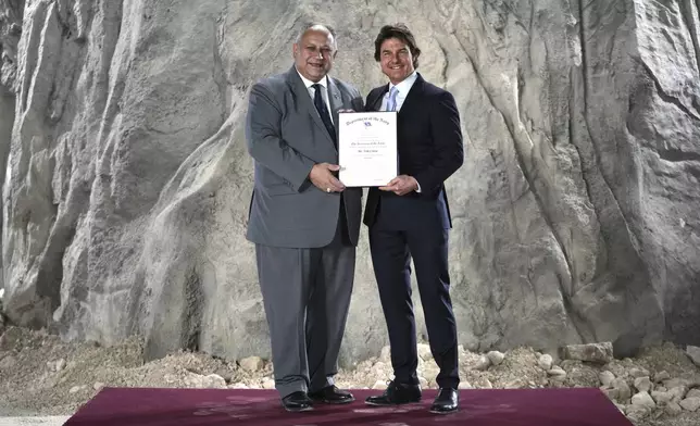 Tom Cruise, right, receives a Navy Distinguished Public Service Award from The United States Secretary of the Navy Carlos Del Toro presents at the Longcross South Studios, in Runnymede, Surrey, England, Tuesday, Dec. 17, 2024. (AP Photo/Kin Cheung)