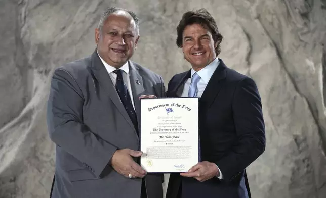 Tom Cruise, right, receives a Navy Distinguished Public Service Award from The United States Secretary of the Navy Carlos Del Toro presents at the Longcross South Studios, in Runnymede, Surrey, England, Tuesday, Dec. 17, 2024. (AP Photo/Kin Cheung)