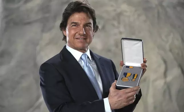 Tom Cruise poses with the Navy Distinguished Public Service Award received from The United States Secretary of the Navy Carlos Del Toro, at the Longcross South Studios, in Runnymede, Surrey, England, Tuesday, Dec. 17, 2024. (AP Photo/Kin Cheung)