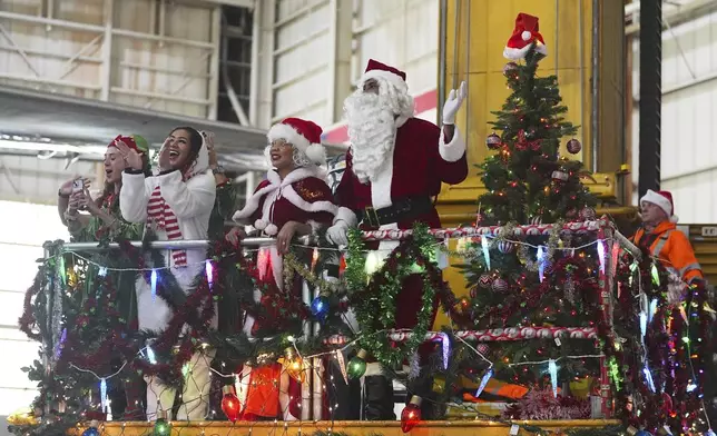 People dressed as Santa Claus and Mrs. Claus greet participants as they disembark from a plane during the United Airlines annual "fantasy flight" to a fictional North Pole at Denver International Airport, Saturday, Dec. 14, 2024, in Denver. (AP Photo/David Zalubowski)