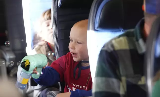 A participant sprays bubbles during the United Airlines annual "fantasy flight" to a fictional North Pole at Denver International Airport, Saturday, Dec. 14, 2024, in Denver. (AP Photo/David Zalubowski)