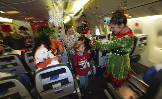 Flight attendant Dre Zulaica, right, of San Francisco, greets 7-year-old Greyson Thomas, of Denver, during the United Airlines annual "fantasy flight" to a fictional North Pole at Denver International Airport, Saturday, Dec. 14, 2024, in Denver. (AP Photo/David Zalubowski)