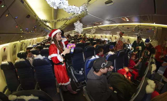 Flight attendant Kaori Kiguradze welcomes participants during the United Airlines annual "fantasy flight" to a fictional North Pole at Denver International Airport, Saturday, Dec. 14, 2024, in Denver. (AP Photo/David Zalubowski)