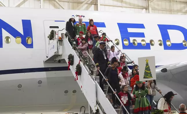 Participants deplane during the United Airlines annual "fantasy flight" to a fictional North Pole at Denver International Airport, Saturday, Dec. 14, 2024, in Denver. (AP Photo/David Zalubowski)