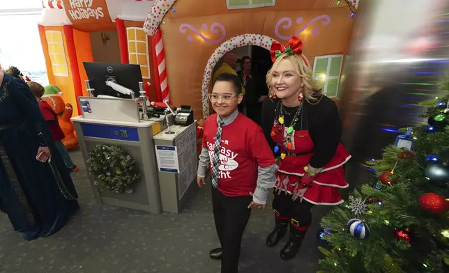 Twelve-year-old Adan Cervantes, left, waits to check in at the gate with the help of a flight attendant during the United Airlines annual "fantasy flight" to a fictional North Pole at Denver International Airport, Saturday, Dec. 14, 2024, in Denver. (AP Photo/David Zalubowski)