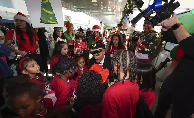 Captain Paul Purkey, center, pins wings on participants during the United Airlines annual "fantasy flight" to a fictional North Pole at Denver International Airport, Saturday, Dec. 14, 2024, in Denver. (AP Photo/David Zalubowski)