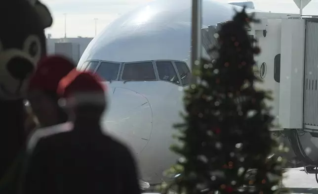 Passengers in holiday garb wait to board an airplane during the United Airlines annual "fantasy flight" to a fictional North Pole at Denver International Airport, Saturday, Dec. 14, 2024, in Denver. (AP Photo/David Zalubowski)