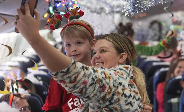 Kaelee Thomas, right, takes a selfie with her 7-year-old son, Greyson, before take off during the United Airlines annual "fantasy flight" to a fictional North Pole at Denver International Airport, Saturday, Dec. 14, 2024, in Denver. (AP Photo/David Zalubowski)