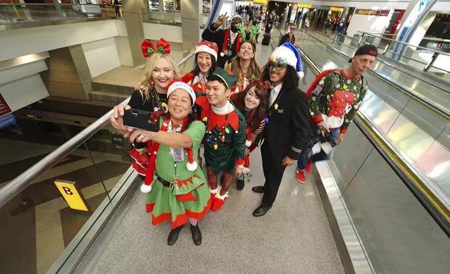 United Airlines employees pose for a photograph as they wait for participants during the company's annual "fantasy flight" to a fictional North Pole at Denver International Airport, Saturday, Dec. 14, 2024, in Denver. (AP Photo/David Zalubowski)