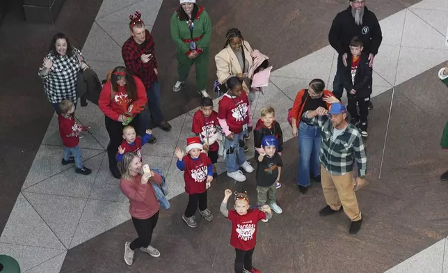 Boys and girls wave as they disembark from the train on their way to the United Airlines annual "fantasy flight" to a fictional North Pole at Denver International Airport, Saturday, Dec. 14, 2024, in Denver. (AP Photo/David Zalubowski)