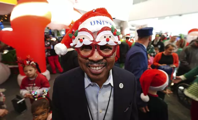 A United Airlines employee dons holiday spectacles during the United Airlines annual "fantasy flight" to a fictional North Pole at Denver International Airport, Saturday, Dec. 14, 2024, in Denver. (AP Photo/David Zalubowski)