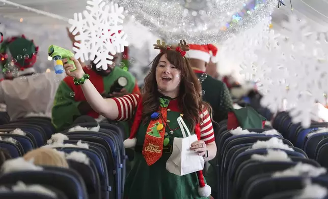 A flight attendant sprays bubbles during the United Airlines annual "fantasy flight" to a fictional North Pole at Denver International Airport, Saturday, Dec. 14, 2024, in Denver. (AP Photo/David Zalubowski)