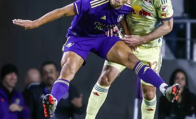 Orlando City forward Ramiro Enrique, left, and New York Red Bulls defender Dylan Nealis, right, head the ball during the first half of an MLS Eastern Conference final soccer match Saturday, Nov. 30, 2024, in Orlando, Fla. (AP Photo/Kevin Kolczynski)