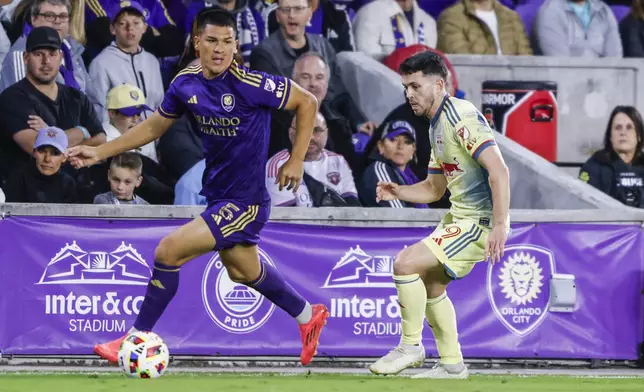 Orlando City midfielder César Araújo, left, is defended by New York Red Bulls midfielder Lewis Morgan, right, during the first half of an MLS Eastern Conference final soccer match, Saturday, Nov. 30, 2024, in Orlando, Fla. (AP Photo/Kevin Kolczynski)