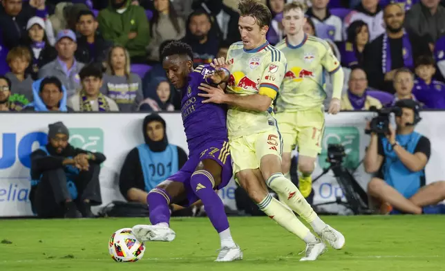 Orlando City forward Iván Angulo, left, is defended New York Red Bulls midfielder Peter Stroud, middle, and forward Cameron Harper, right, during the first half of an MLS Eastern Conference final soccer match, Saturday, Nov. 30, 2024, in Orlando, Fla. (AP Photo/Kevin Kolczynski)