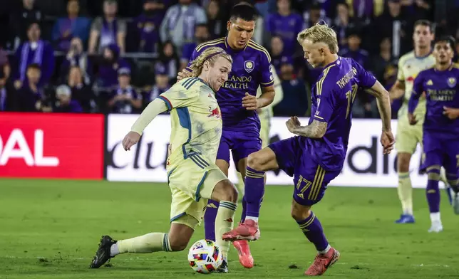 New York Red Bulls midfielder Emil Forsberg, left, is defended by Orlando City midfielder César Araújo, middle, and Orlando City midfielder Dagur Dan Þórhallsson, right, during the first half of an MLS Eastern Conference final soccer match, Saturday, Nov. 30, 2024, in Orlando, Fla. (AP Photo/Kevin Kolczynski)