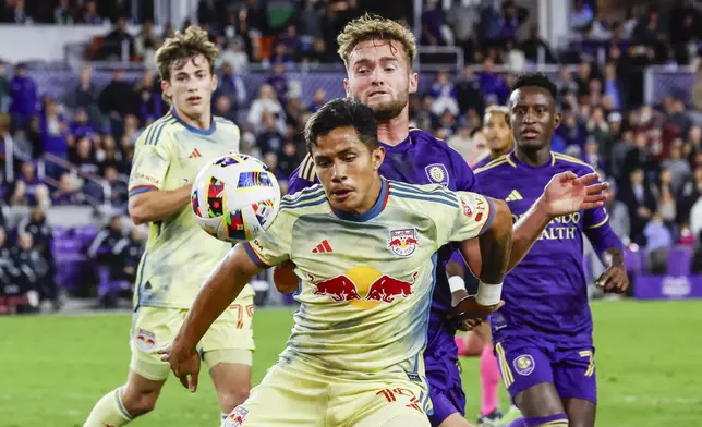 New York Red Bulls midfielder Wikelman Carmona, front, defends the ball against Orlando City forward Duncan McGuire,center top,, during the second half of an MLS Eastern Conference final soccer match, Saturday, Nov. 30, 2024, in Orlando, Fla. (AP Photo/Kevin Kolczynski)