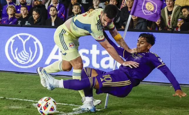 New York Red Bulls defender Dylan Nealis, top, and Orlando City forward Facundo Torres (10) fight for ball during the second half of an MLS Eastern Conference final soccer match, Saturday, Nov. 30, 2024, in Orlando, Fla. (AP Photo/Kevin Kolczynski)