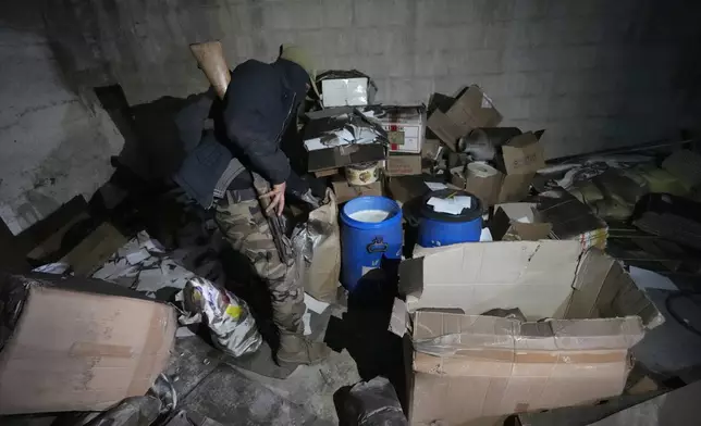 A Syrian member of the rebel group inspect material for manufacturing amphetamine pills, known as Captagon, hidden at the warehouse where the drug was manufactured before the fall of Bashar Assad government at a facility in Douma city, outskirts of Damascus, Syria, Friday, Dec. 13, 2024. (AP Photo/Hussein Malla)