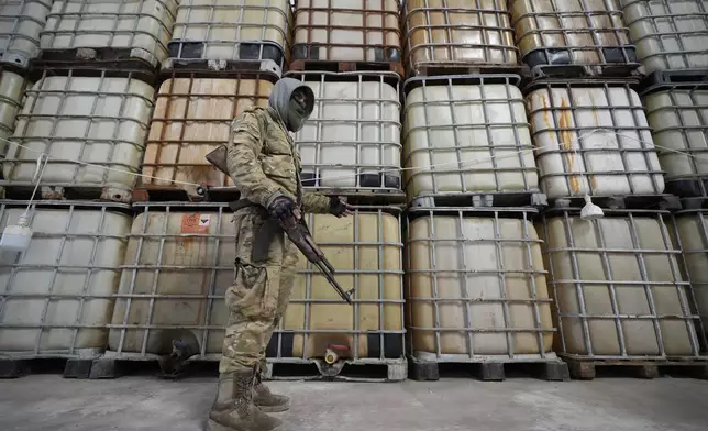 A Syrian member of the rebel group shows liquid material for manufacturing amphetamine pills known as Captagon hidden, at the warehouse where the drug was manufactured before the fall of Bashar Assad government at a facility in Douma city, outskirts of Damascus, Syria, Friday, Dec. 13, 2024. (AP Photo/Hussein Malla)