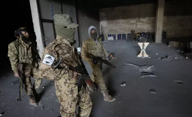 Syrian members of the rebel group walk at a warehouse where the amphetamine pills known as Captagon was manufactured before the fall of Bashar Assad government in Douma city, outskirts of Damascus, Syria, Friday, Dec. 13, 2024. (AP Photo/Hussein Malla)