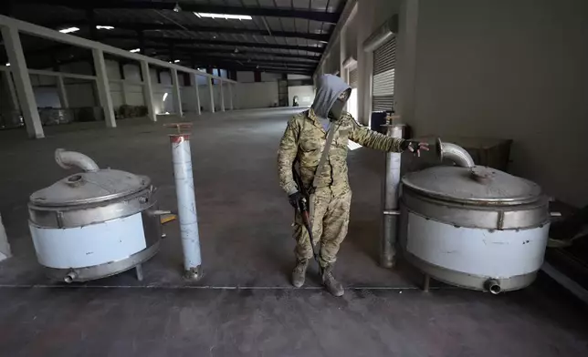 A Syrian member of the rebel group shows machines that were used to manufacturing amphetamine pills known as Captagon, at the warehouse where the drug was manufactured before the fall of Bashar Assad government at a facility in Douma city, outskirts of Damascus, Syria, Friday, Dec. 13, 2024. (AP Photo/Hussein Malla)