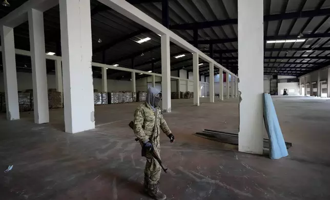 A Syrian member of the rebel group walks at a warehouse where the amphetamine pills known as Captagon were manufactured before the fall of Bashar Assad government in Douma city, outskirts of Damascus, Syria, Friday, Dec. 13, 2024. (AP Photo/Hussein Malla)