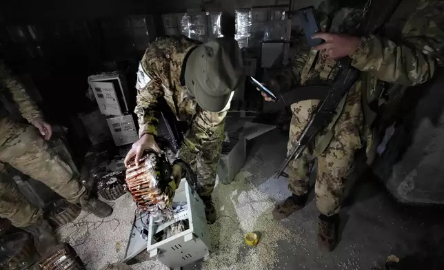 A Syrian member of the rebel group unloads amphetamine pills, known as Captagon, hidden inside an electrical component at the warehouse where the drug was manufactured before the fall of Bashar Assad government at a facility in Douma city, outskirts of Damascus, Syria, Friday, Dec. 13, 2024. (AP Photo/Hussein Malla)